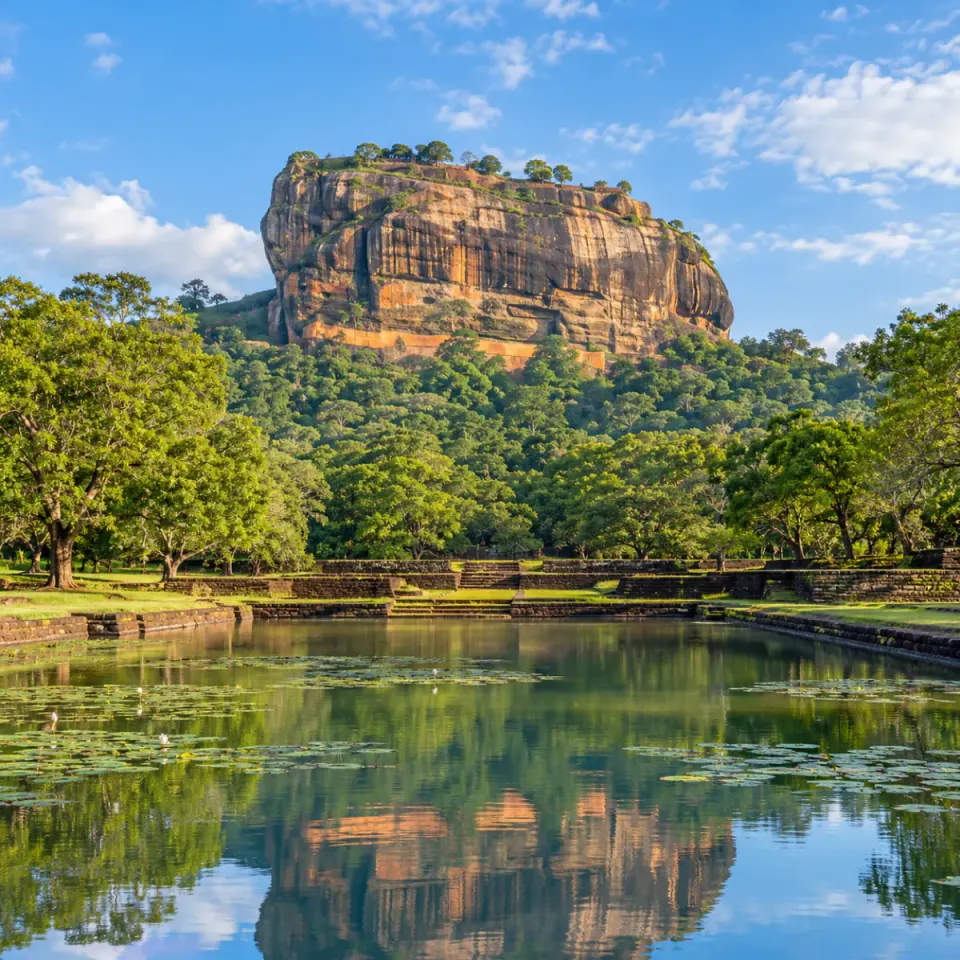 Sigiriya rock reflected in a pond surrounded by green forest
